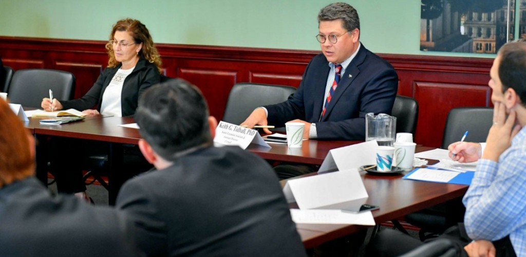 A group of legislators and other government workers discuss in a legislation room