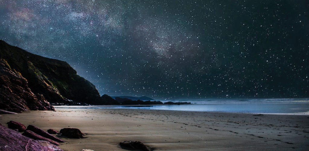 Milky Way galaxy arcs over an ocean beach at night