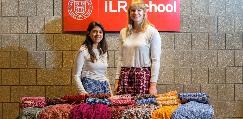 Two female students standing behind a table of colorful pants