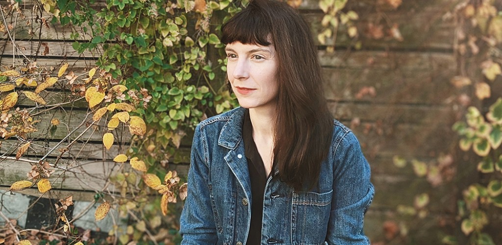 Anne Weber sitting in front of an ivy covered brick wall