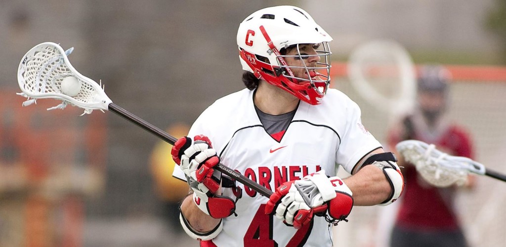 a male lacrosse player raises his stick