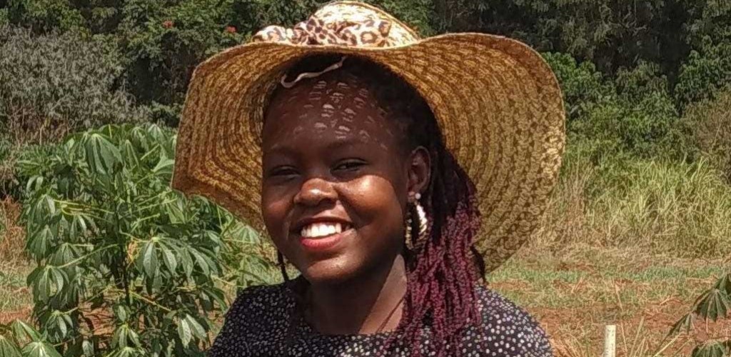 Leah Nandudu stands outside in a cassava field