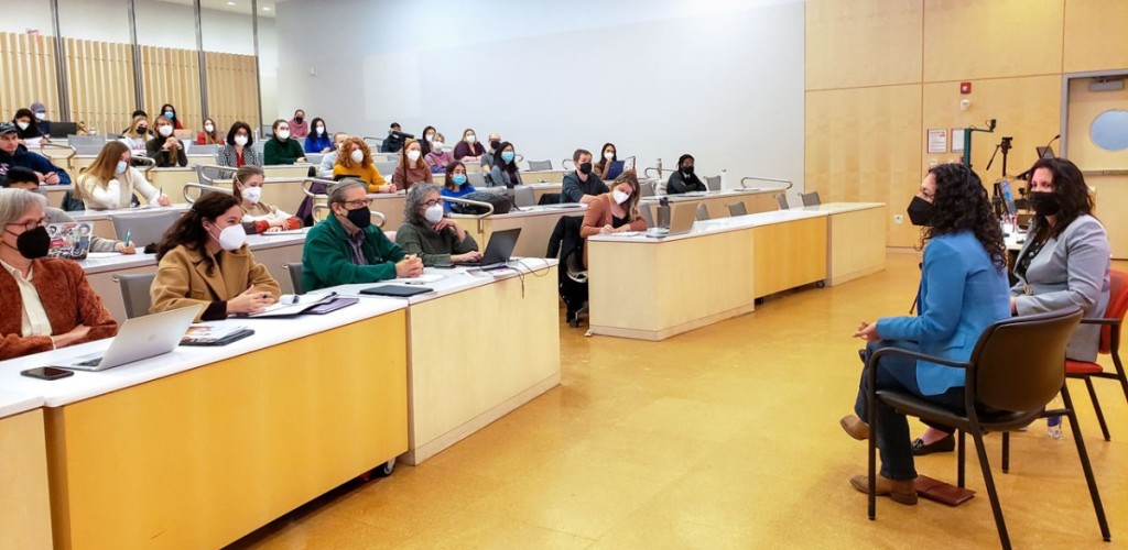 Xochitl Torres Small sitting in front of a room of people in Stocking Hall and talking