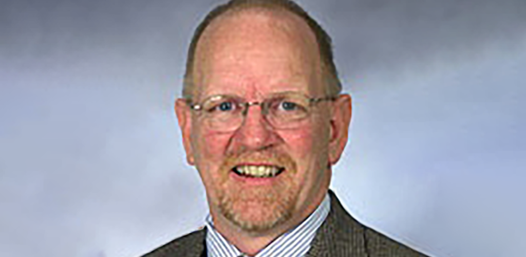 a man in a suit and tie with glasses in front of a blue wall