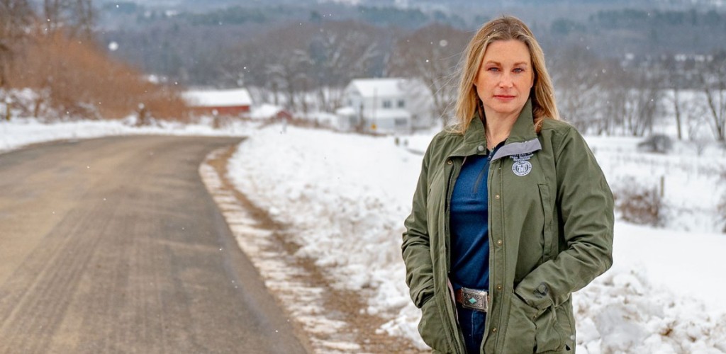 A woman stands by a wintery rural road