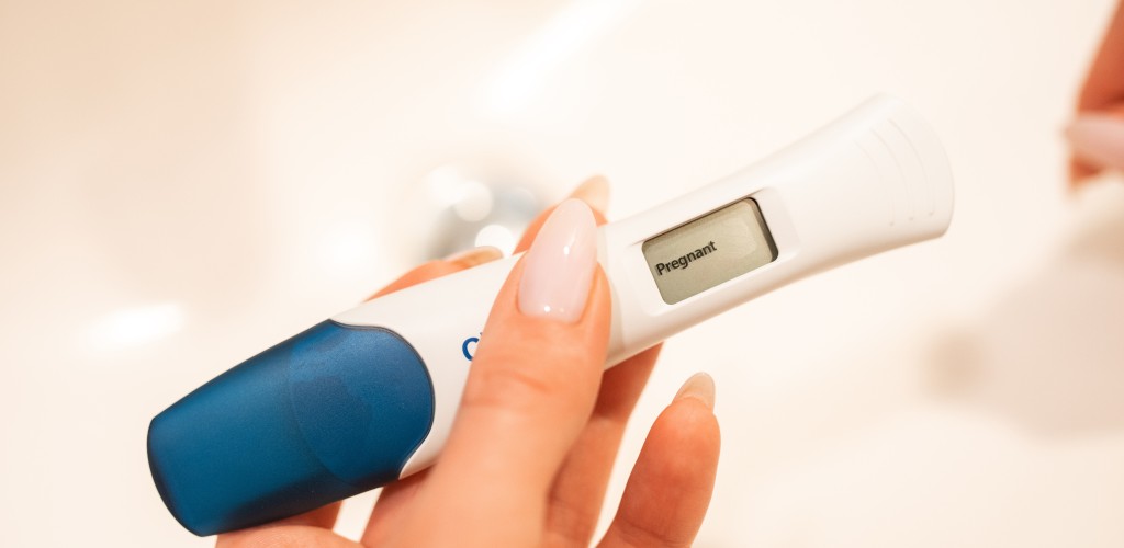 Hands holding a positive pregnancy test. 