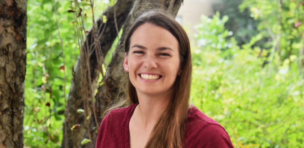 Headshot of Carly Bass smiling in front of a tree