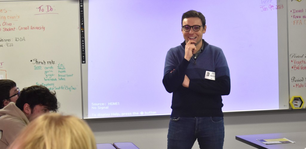 a man stands in front of students, teaching