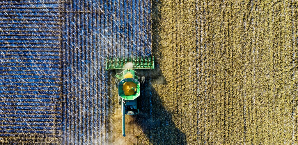 An aerial view of a tractor cutting down field crops.