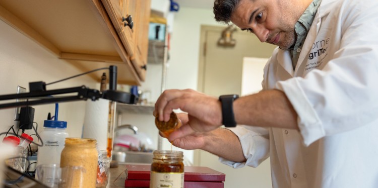 A man using an eye dropper to test a jar of mushroom sauce. 