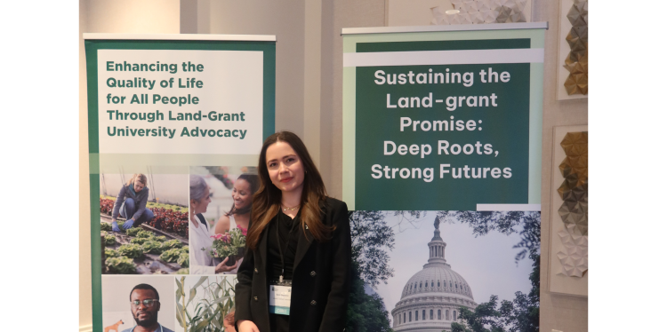 Kate Stephens ’26 posing next to banners at the CARET conference