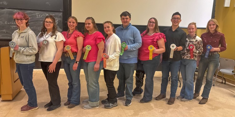 a croup of teenagers stand in a line holding ribbon awards