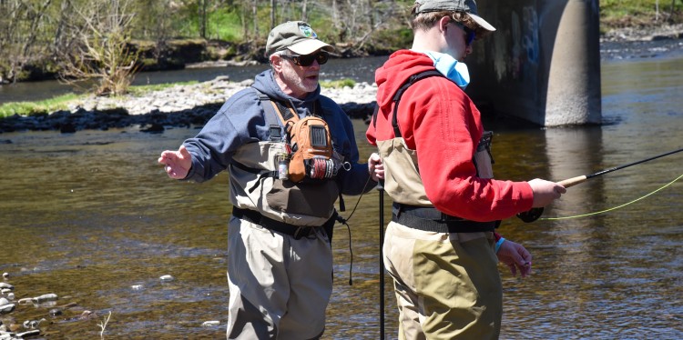 A Trout Unlimited volunteer on stream with a 4-H youth participant