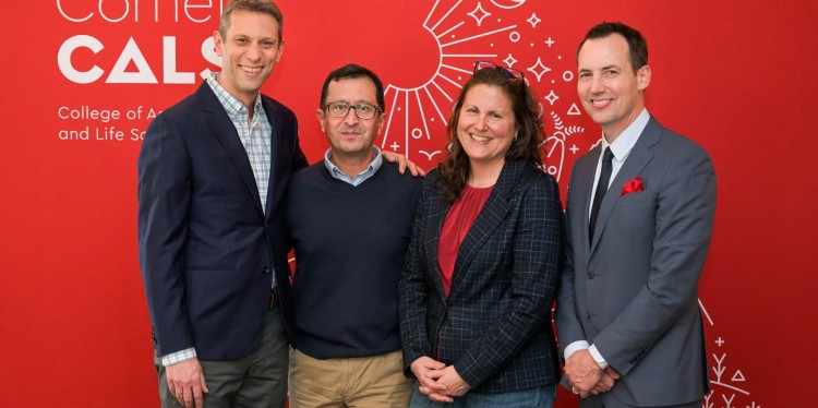 four people stand in front of a red background with the CALS logo on it