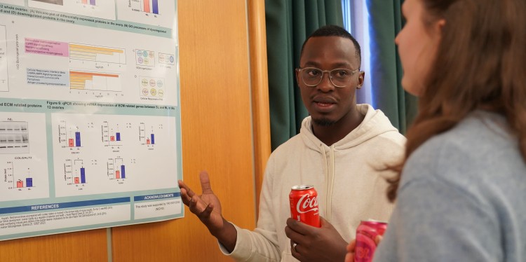 a man gestures at a poster on the wall as he talks to a woman