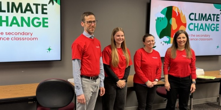 Four individuals in red t-shirts stand in a classroom next to screens displaying "CLIMATE CHANGE."