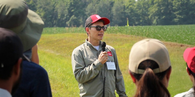 Louis Longchamps speaking to a group of people at a farm