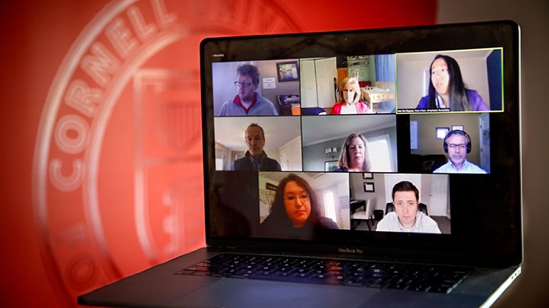 A laptop screens shows 7 people on a Zoom call.