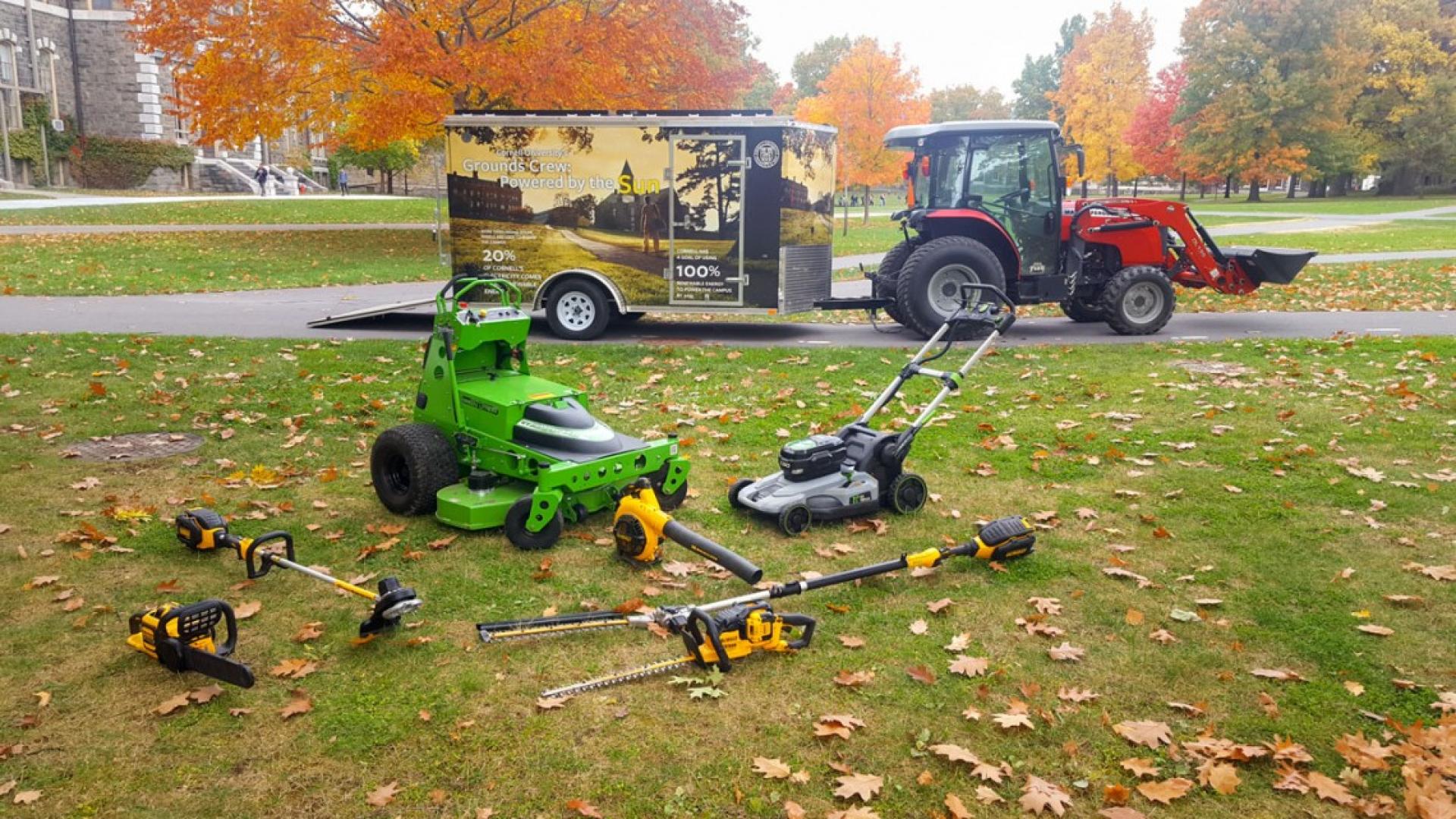 A tractor pulling a trailer with several lawn care tools 