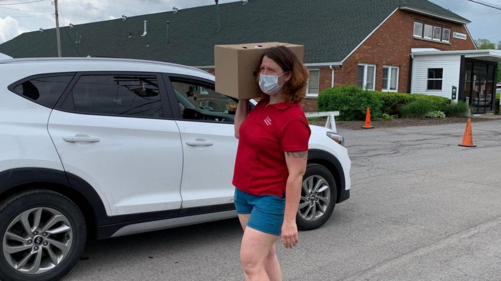 CCE staff member carries food box on their shoulder