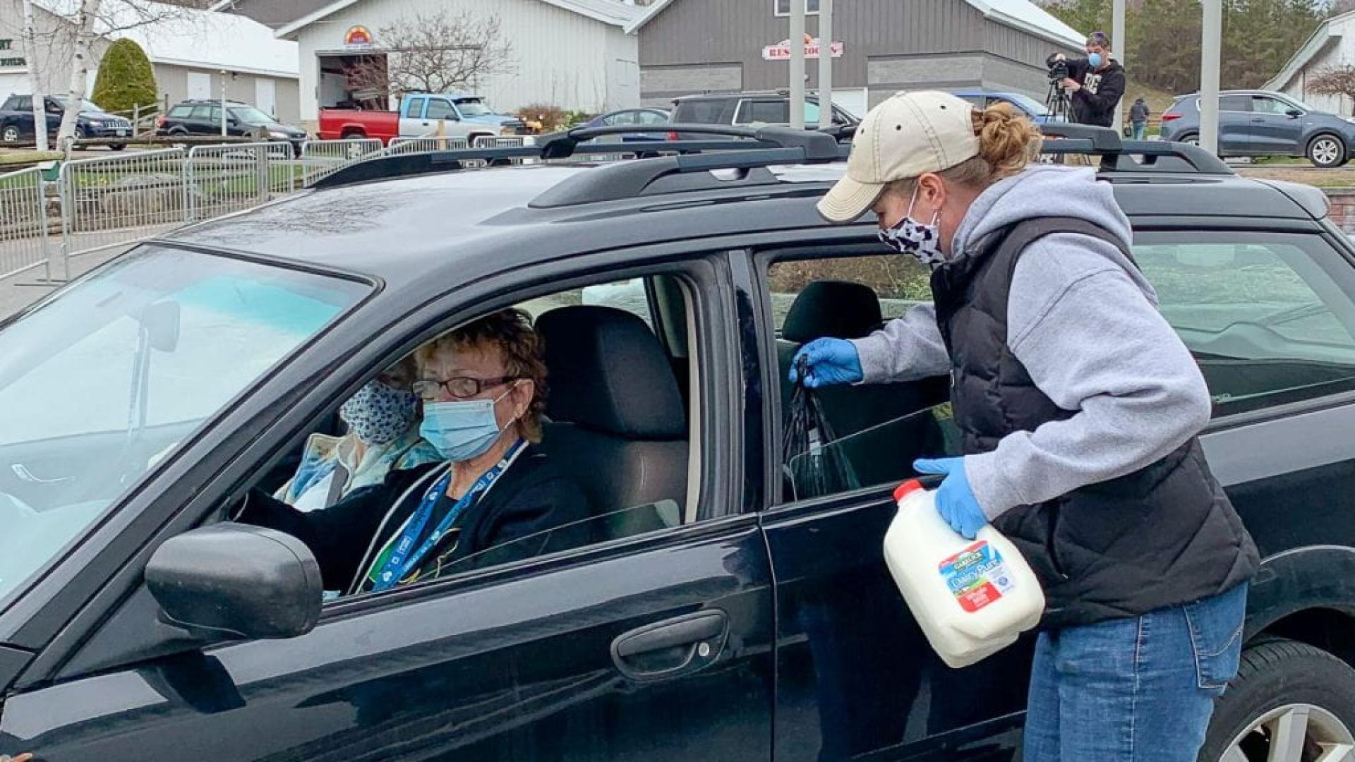 woman delivers milk to people in car