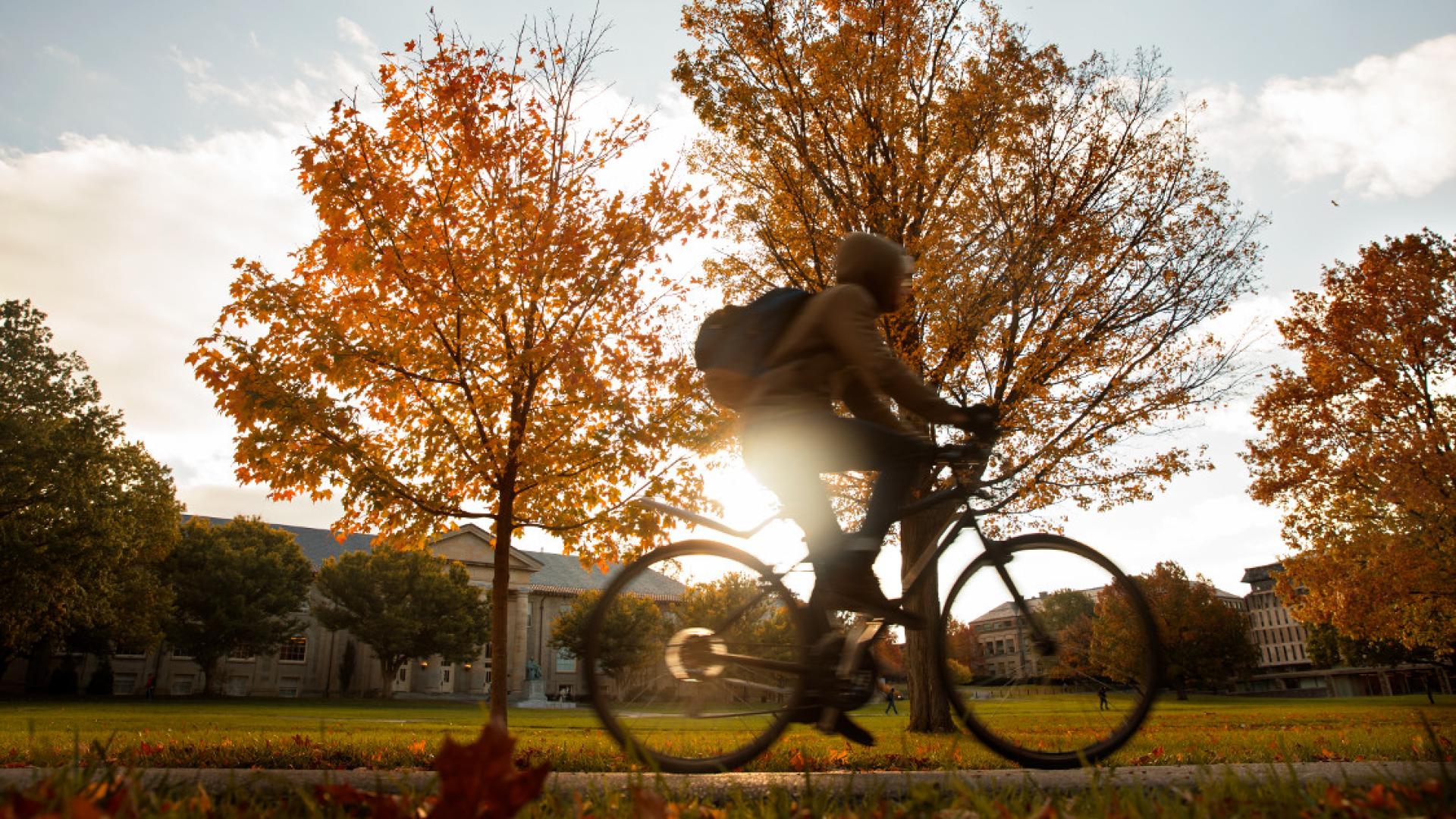 A student riding a bike in a college quad