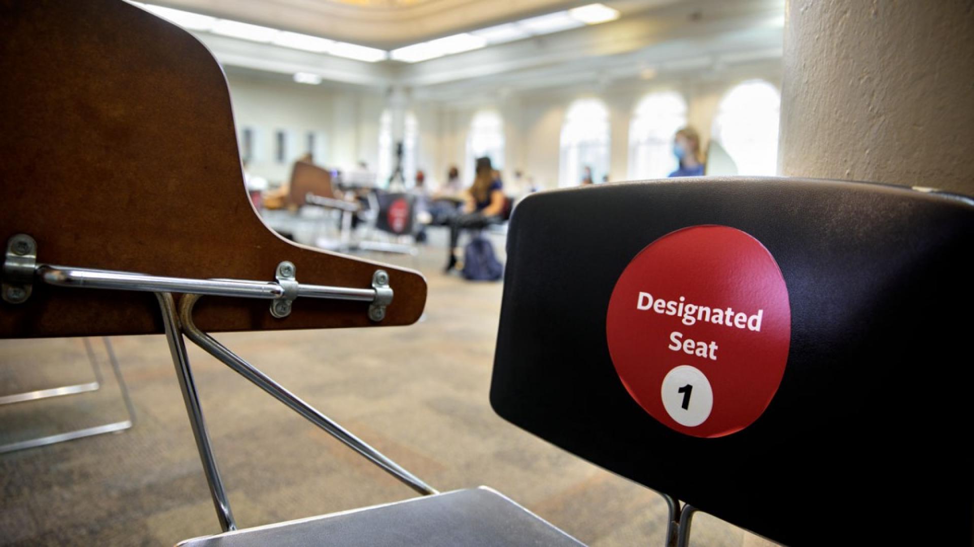 a desk that has a red sticker on it reading "designated seat 1"