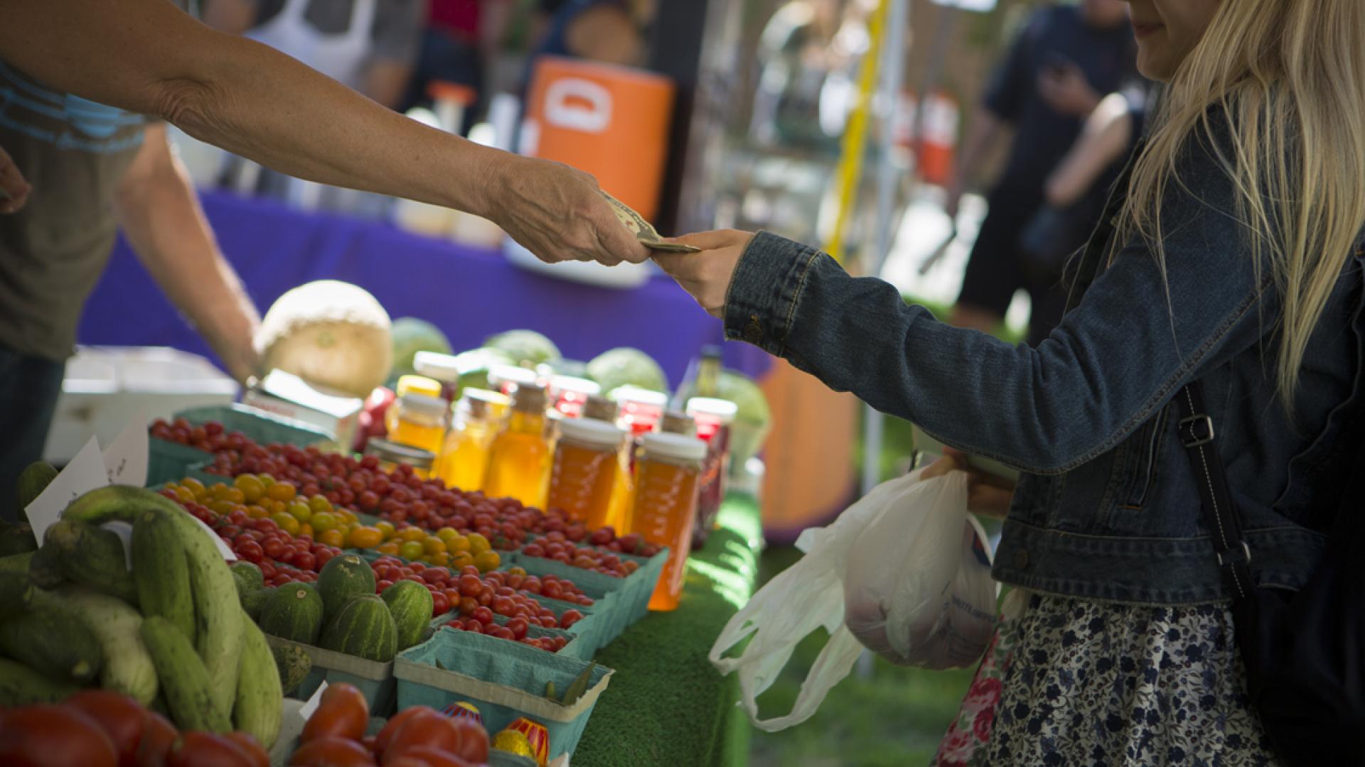 Two people exchanging money at a farmers market
