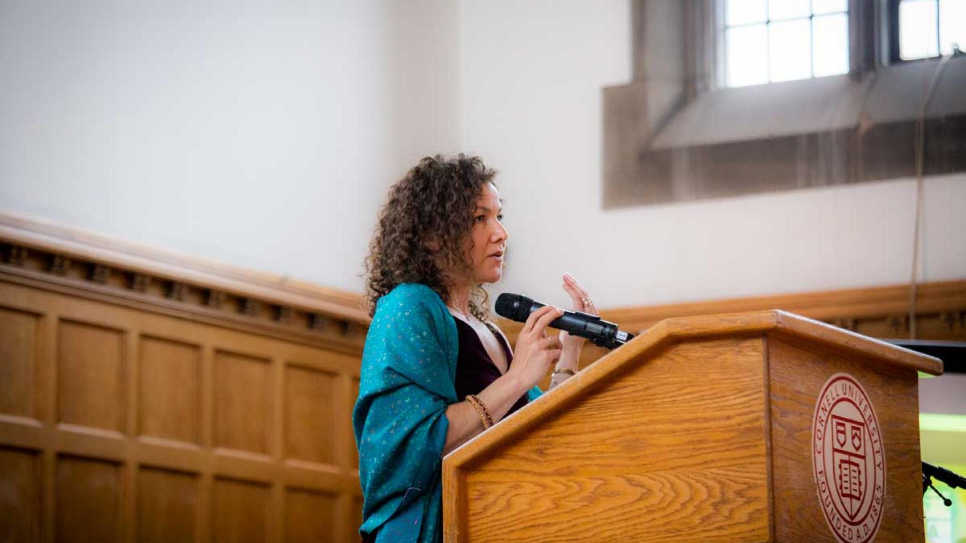 Polly Endreny Holmberg at a lectern speaking into a microphone