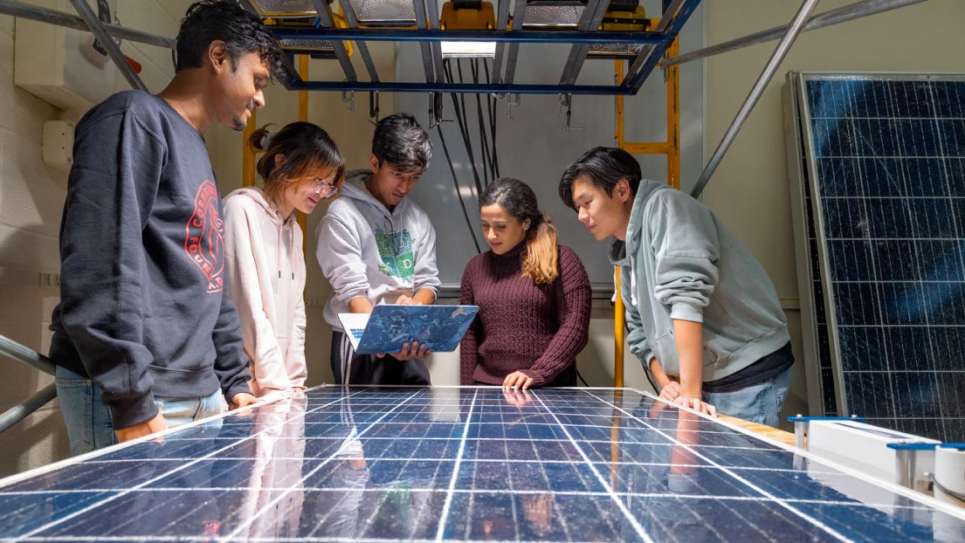 Members of the Solar Panel Reboot team stand around a solar panel