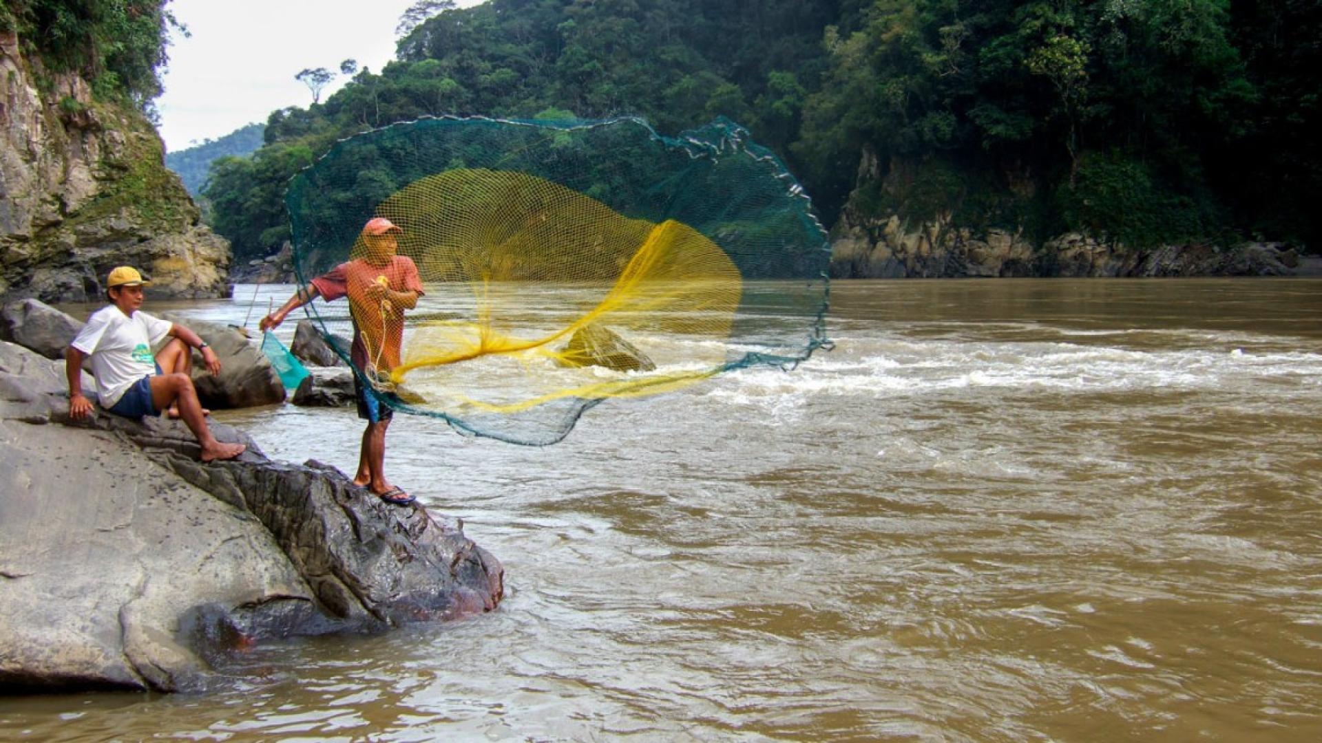 Fishermen cast their nets in the Amazon River.