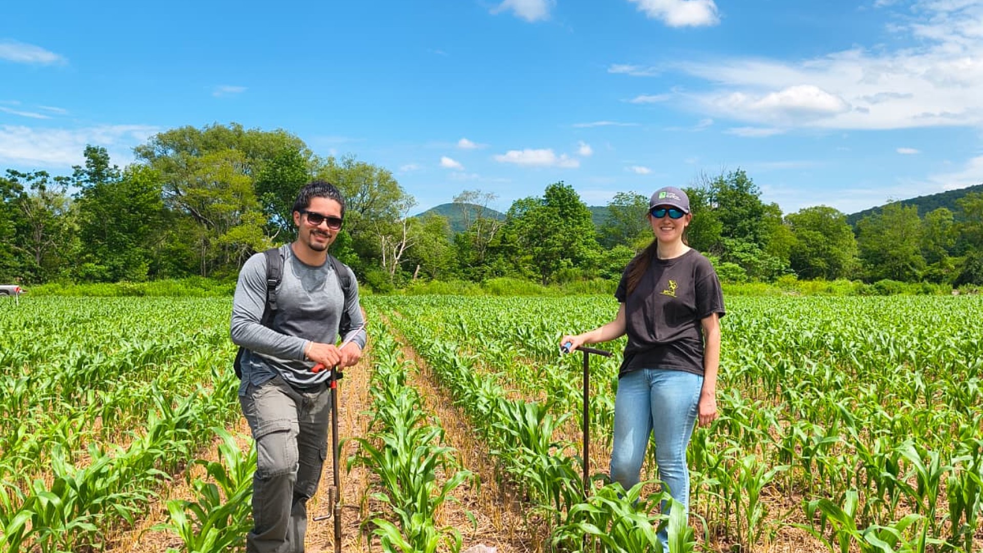 Two people standing in a field with equipment.