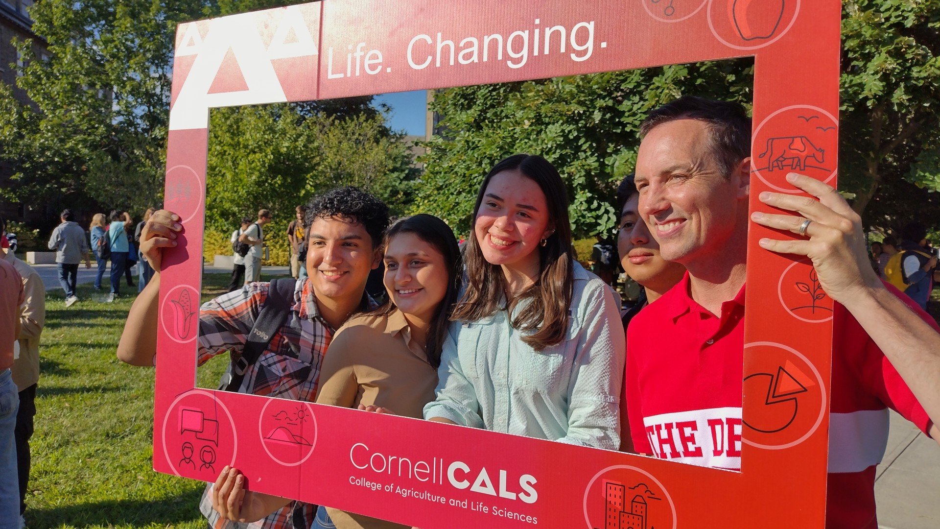 Four people stand with their faces inside a Cornell CALS themed frame.
