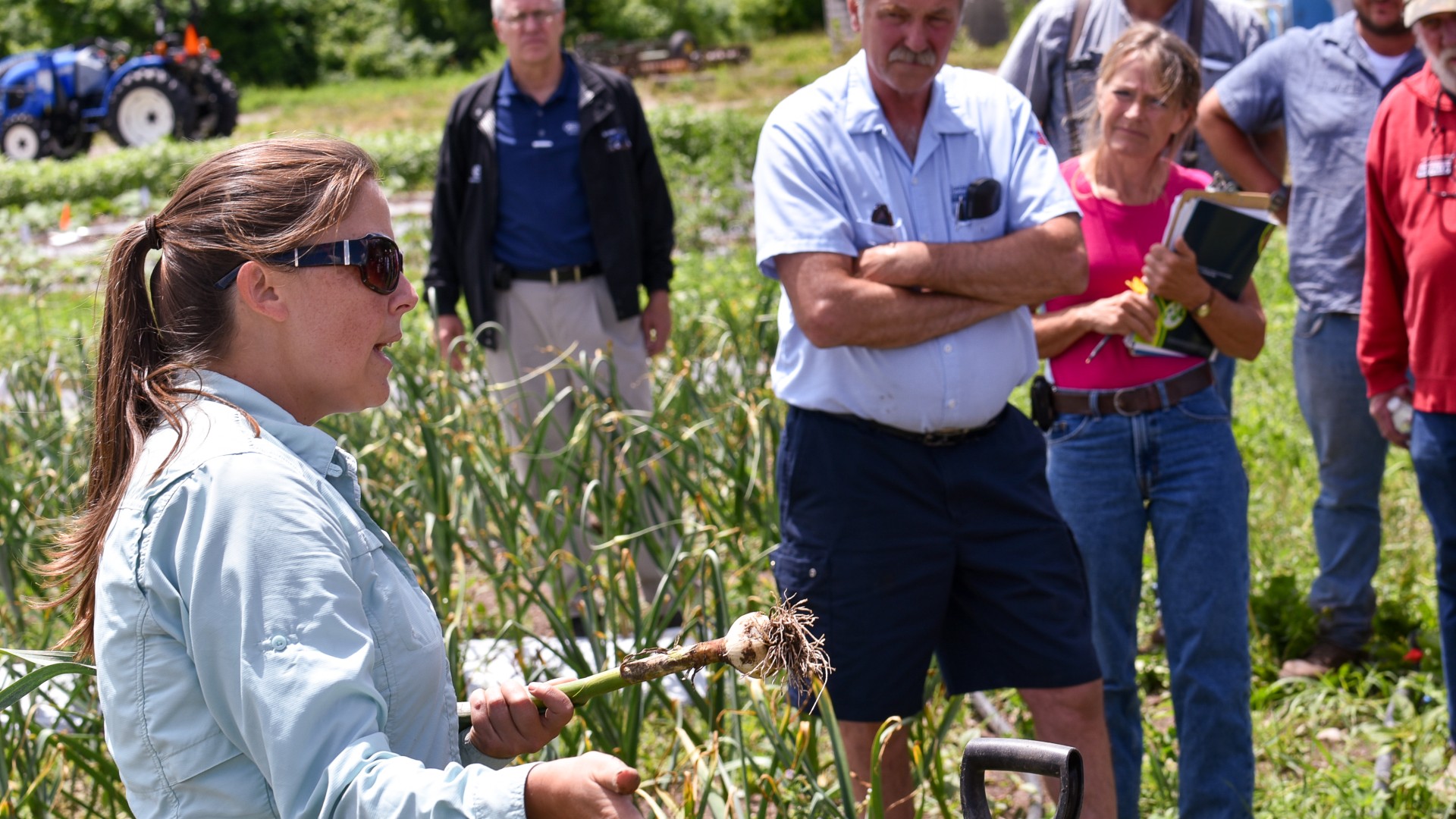 Crystal Stewart Courtens at CCE field day holding garlic and speaking to attendees