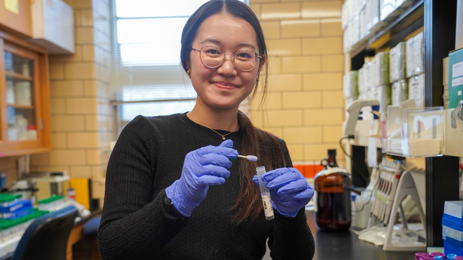 a woman holds a vial of liquid in a lab