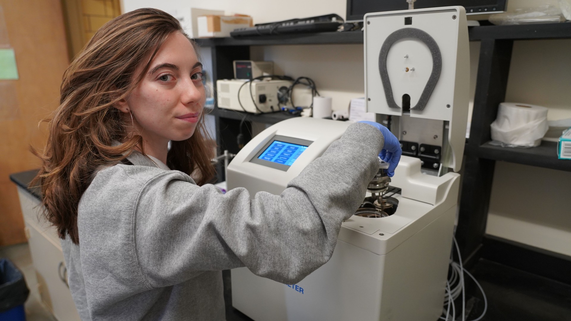 a woman puts a sample into a bombcalorimeter
