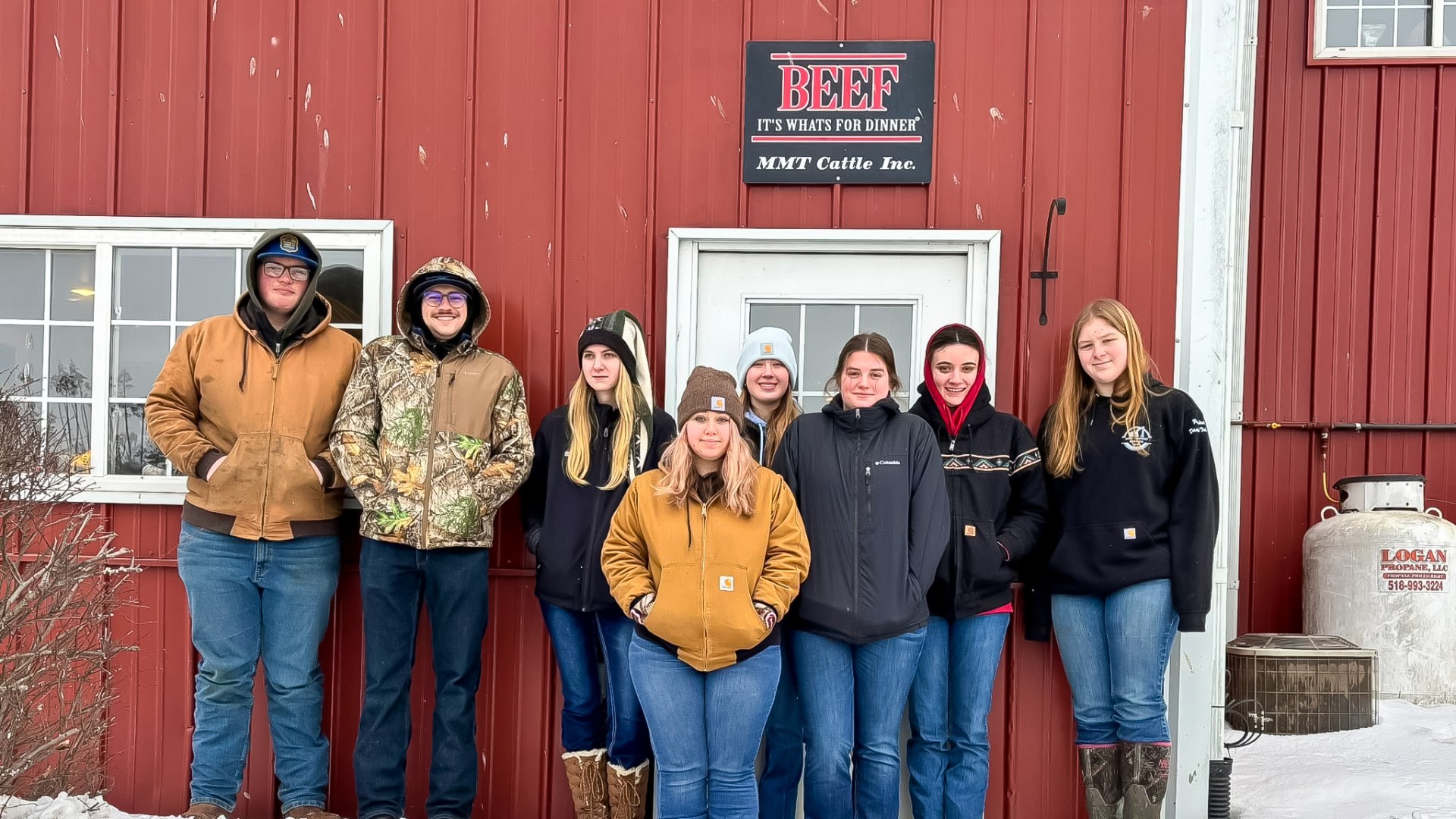 a group of young people stand together in front of a building