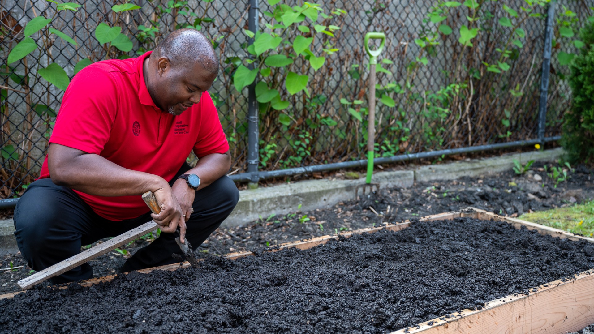 Kwesi Joseph at a raised bed, holding a trowel