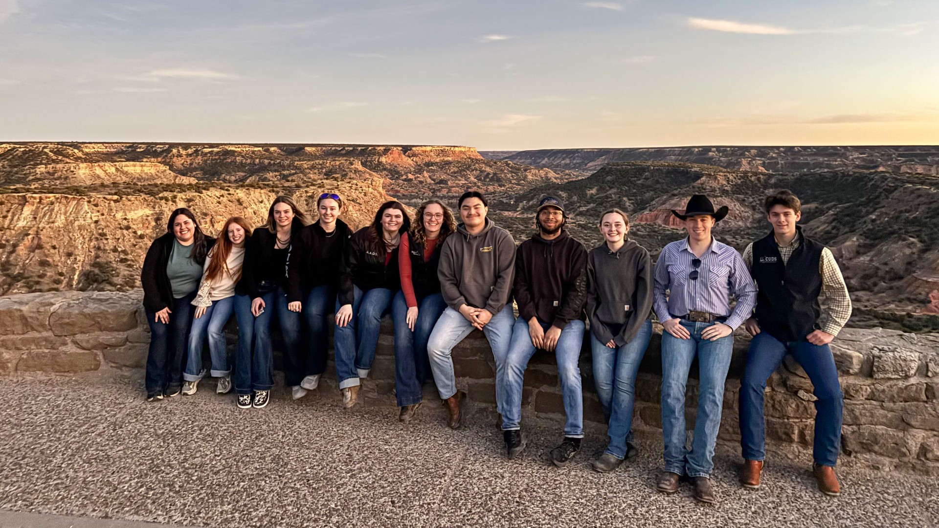 a group of people stand infront of a canyon landscape