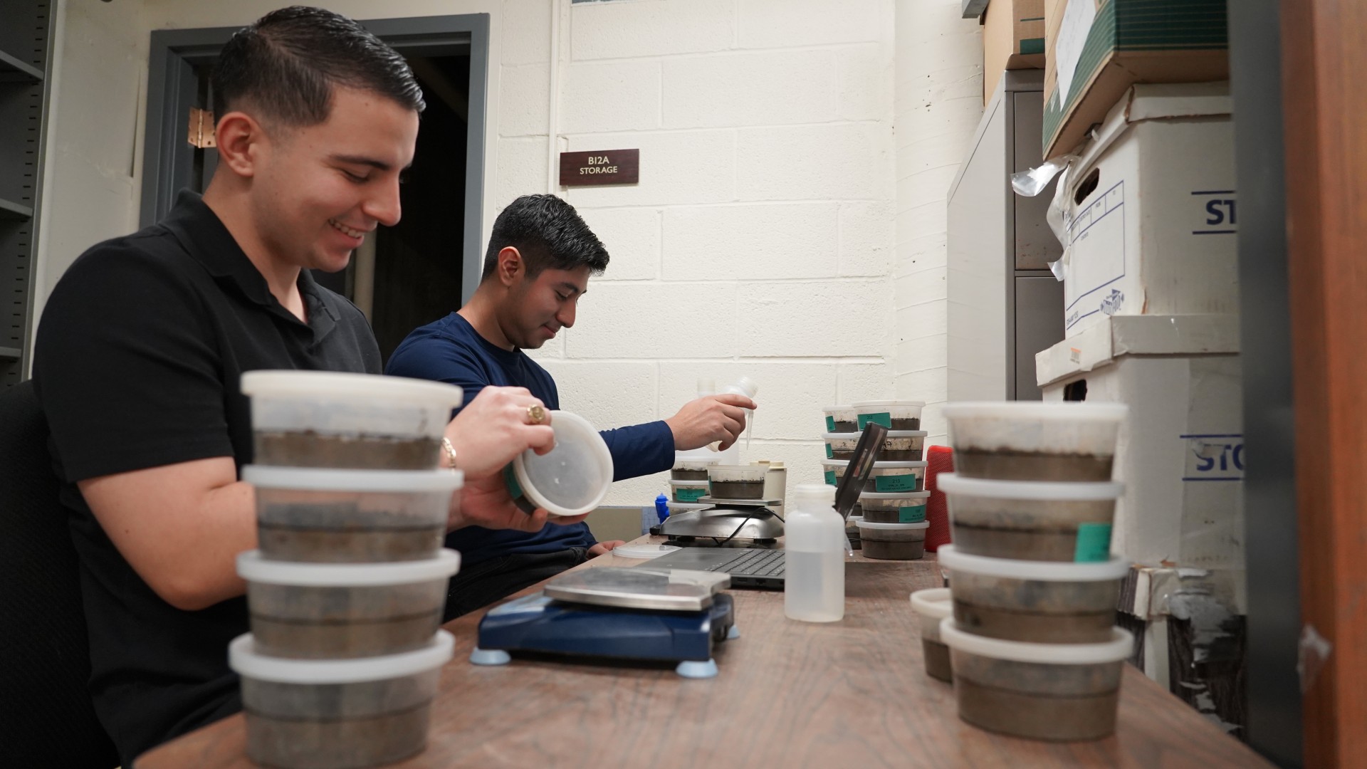 Two people work with scientific equipment on a desk.
