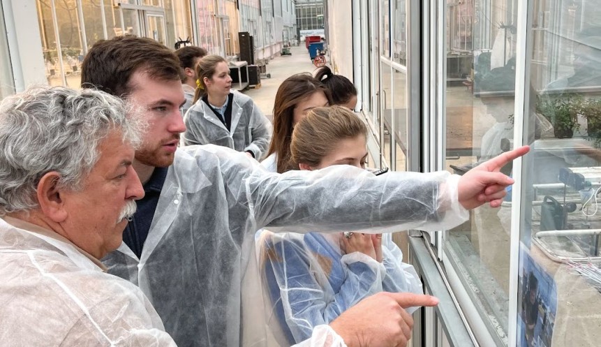 Professor and students stand in front of a glass wall