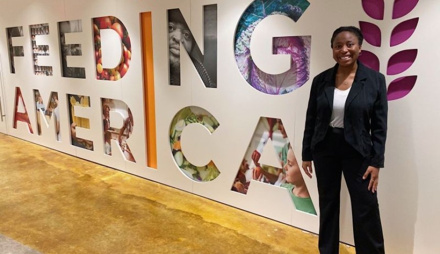 person in a suit standing in front of a sign that reads feeding america