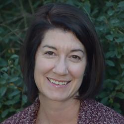 portrait of a woman in a patterned shirt in front of a hedge