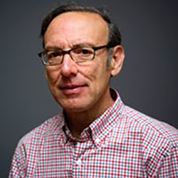 a man in a pink checkered shirt and glasses