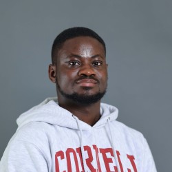 person standing in front of a grey background in a Cornell Sweatshirt