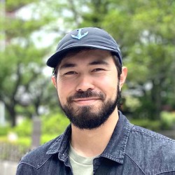 Photo of a person in a hat standing in front of plants