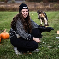 a woman crouches with a hawk on her arm