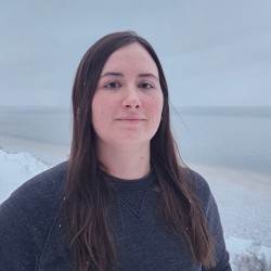 a woman in a blue shirt stands in front of a snowy landscape