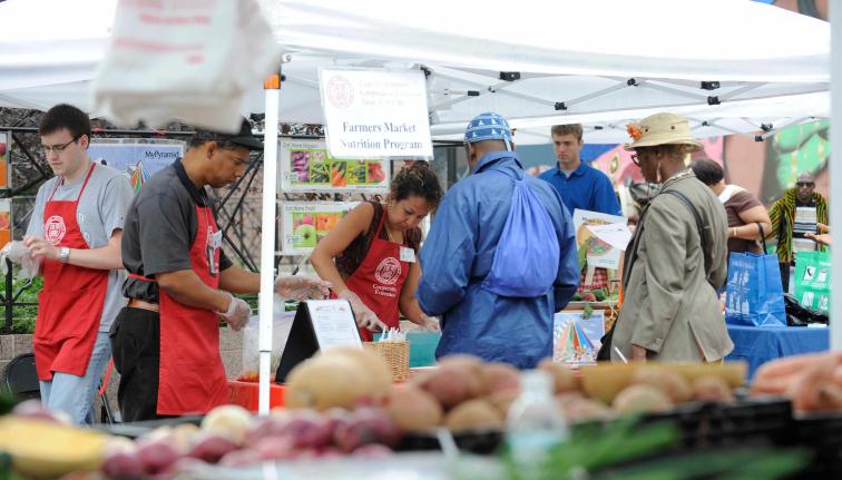 Small group under a tent at farmers market in the Bronx