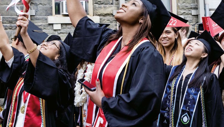 Cornell graduates in regalia waving pennants 